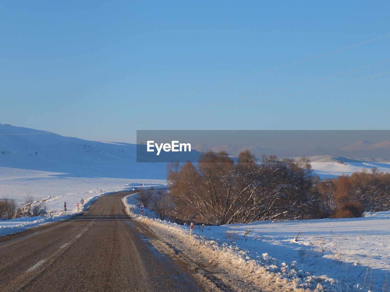 Road amidst snowcapped landscape against sky during winter