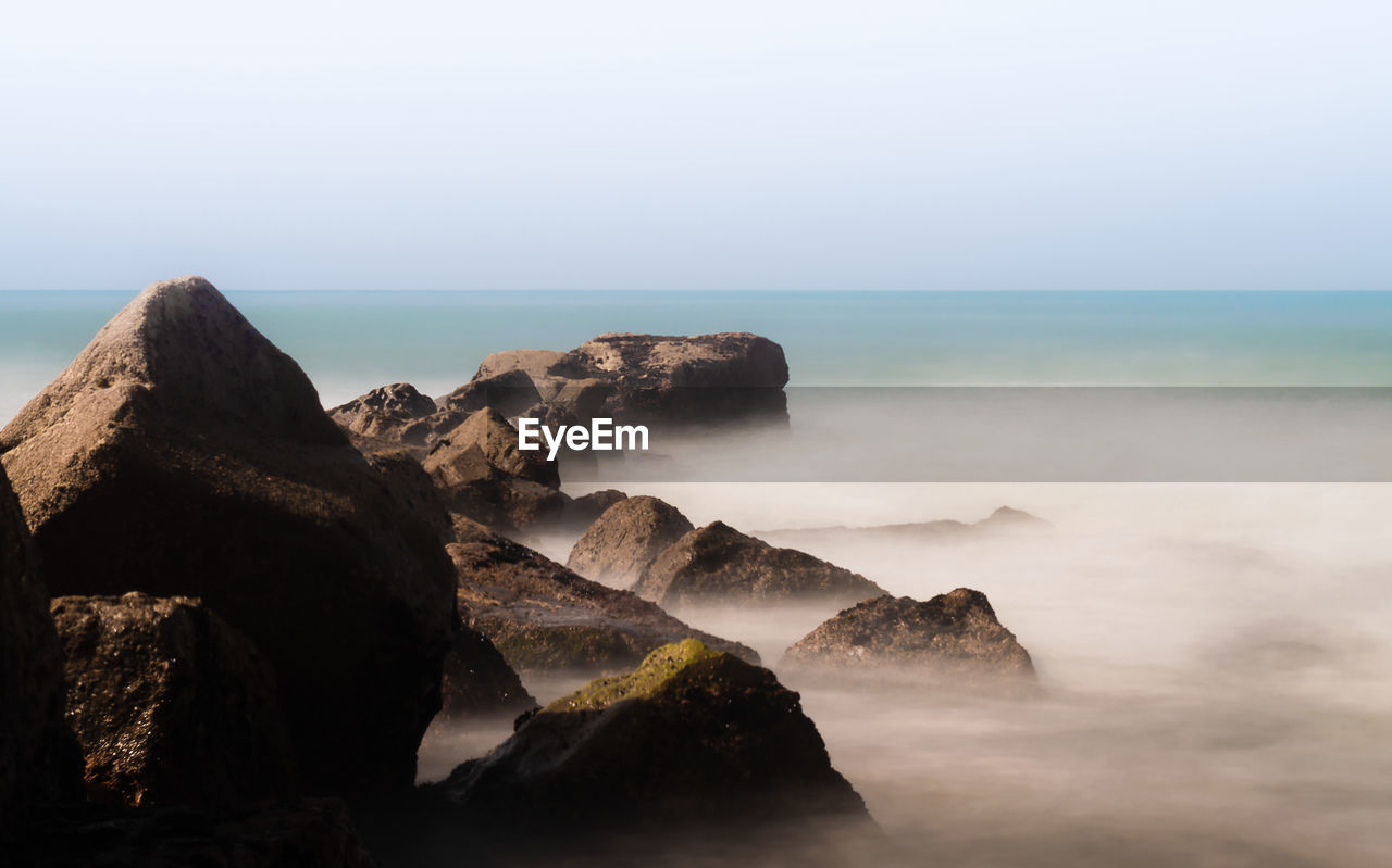 Scenic view of rocks in sea against sky