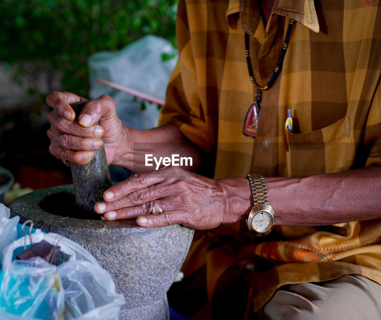 Close-up of man using mortal and pestle