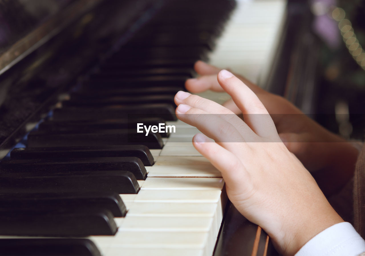 CROPPED IMAGE OF CHILD PLAYING PIANO