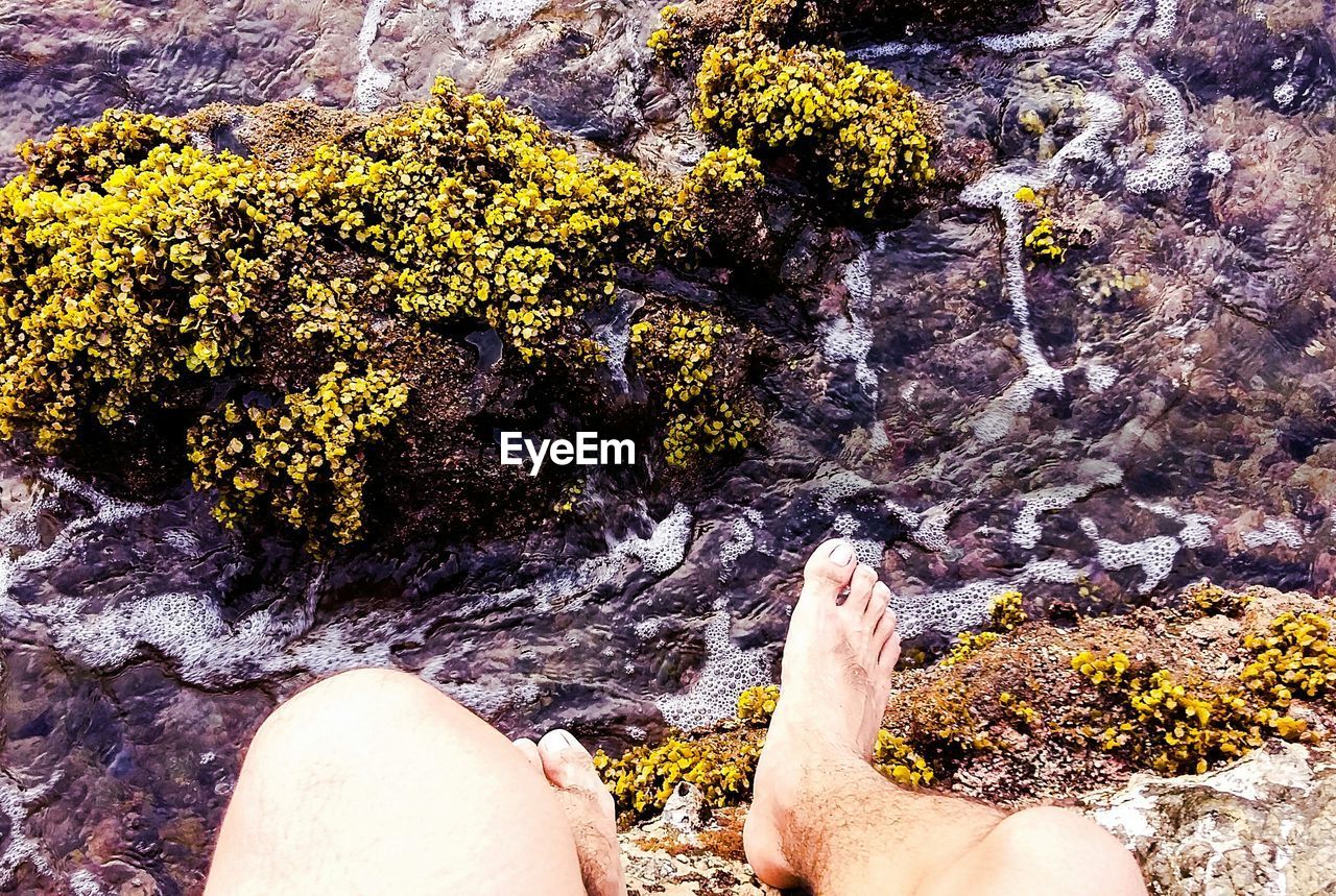 Low section of man sitting on cliff