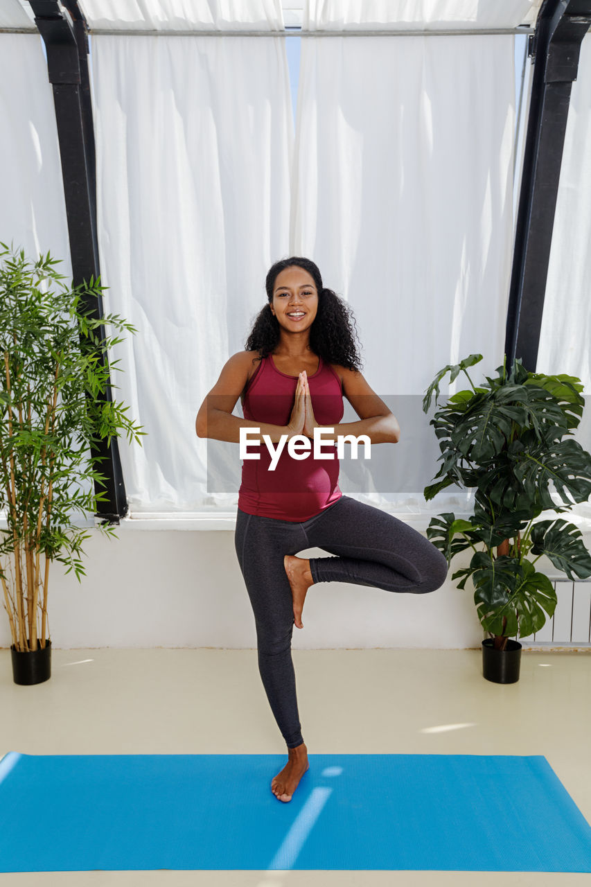 Portrait of pregnant young woman practicing yoga at home