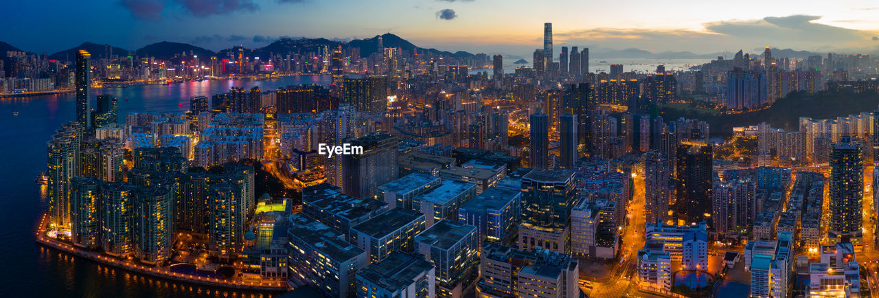 Panoramic view of illuminated buildings in city against sky at dusk