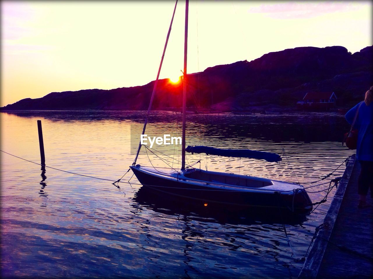 Boat moored in lake against sky during sunset