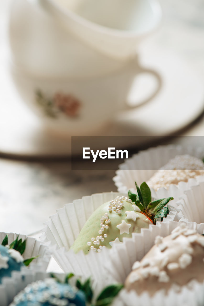 Step by step. tasty blue chocolate dipped strawberries with sugar sprinkles  with a tea cups 