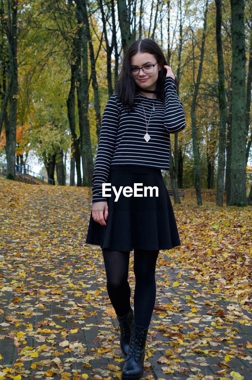 Portrait of smiling woman standing in park during autumn