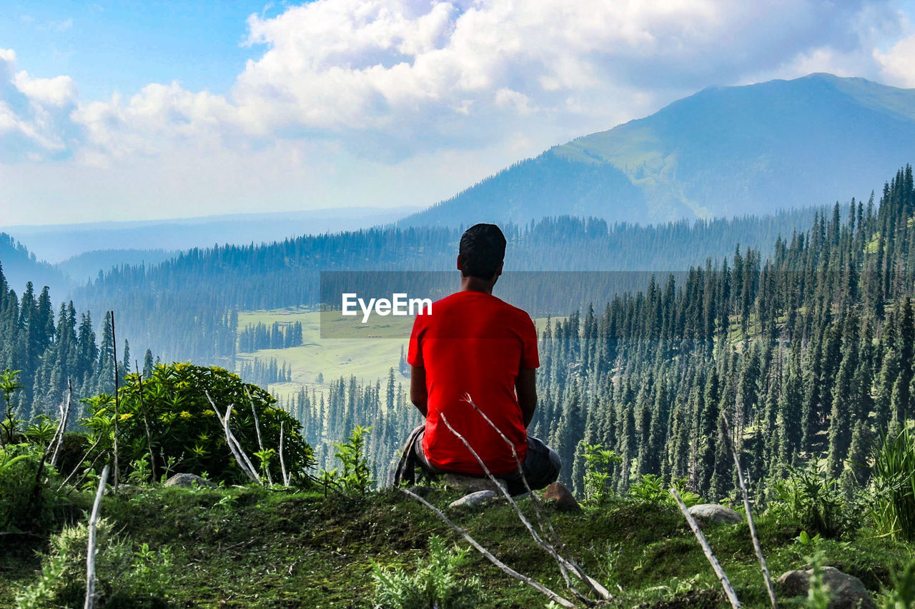 Rear view of man looking at mountains against sky