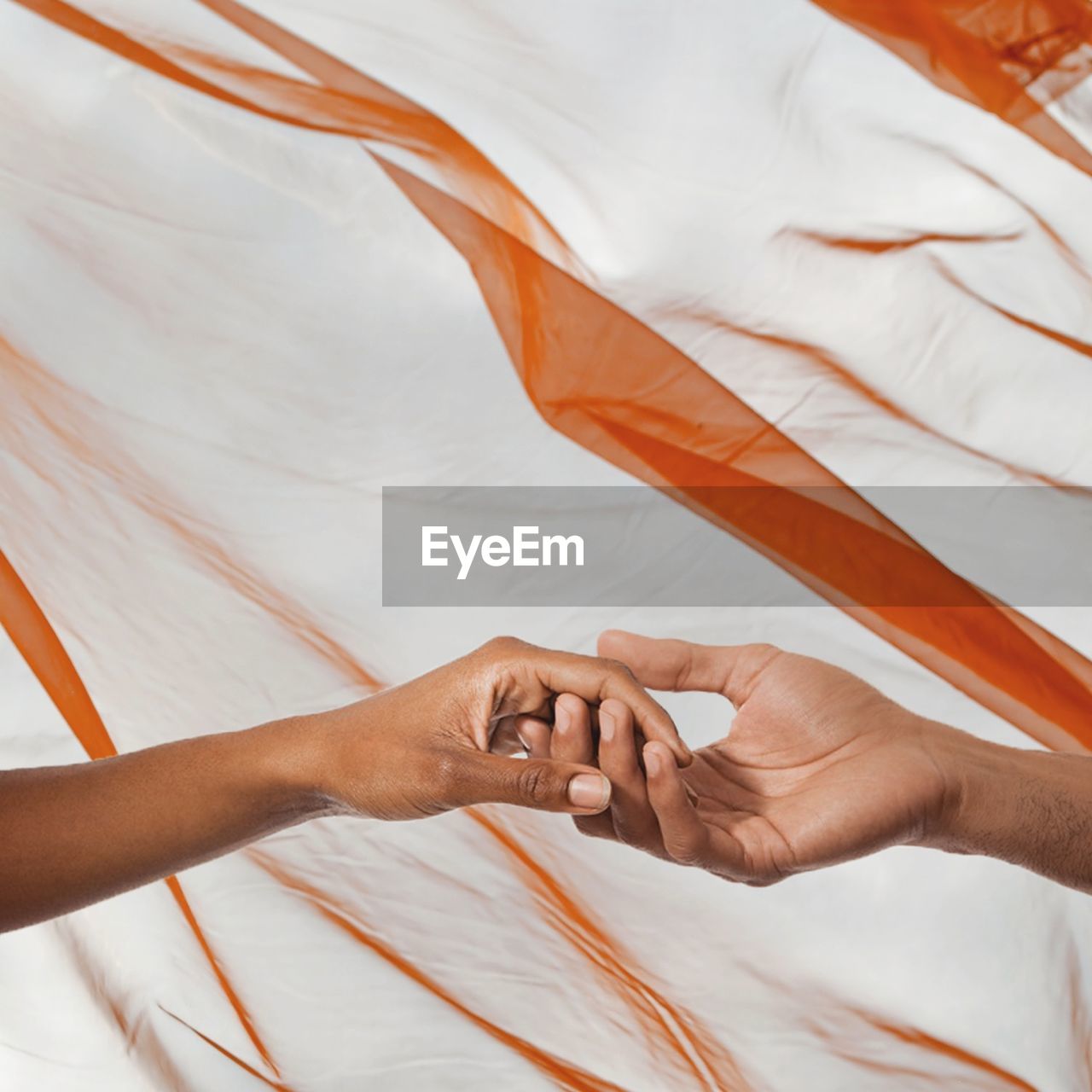 Cropped image of couple holding hands against textile