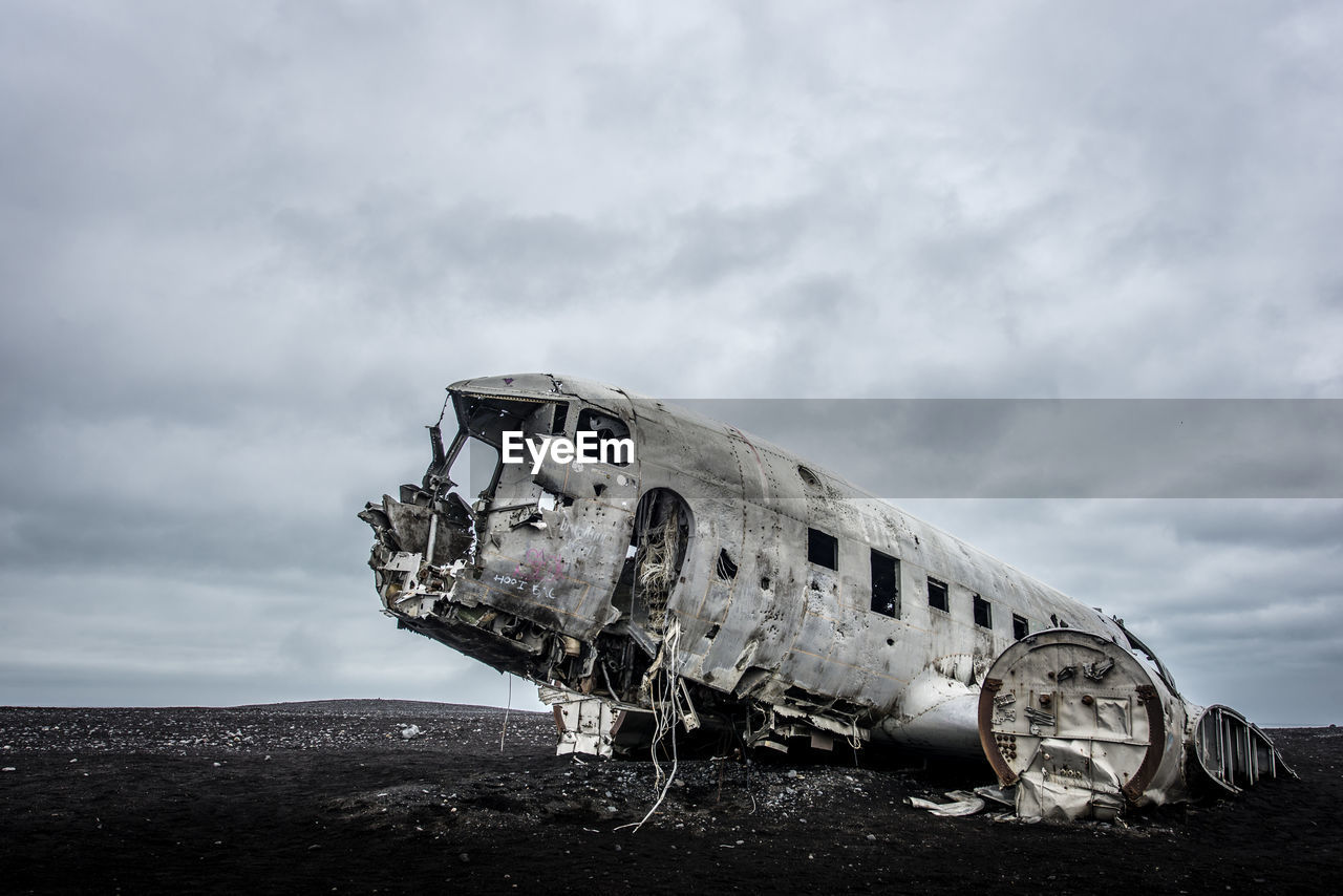 Abandoned airplane against cloudy sky