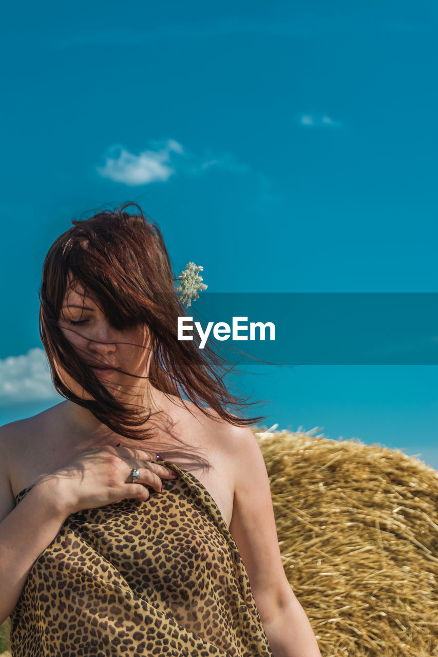 Portrait of woman standing against blue sky