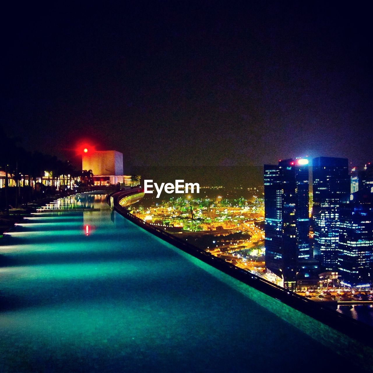Illuminated cityscape against clear sky seen from infinity pool of marina bay sands