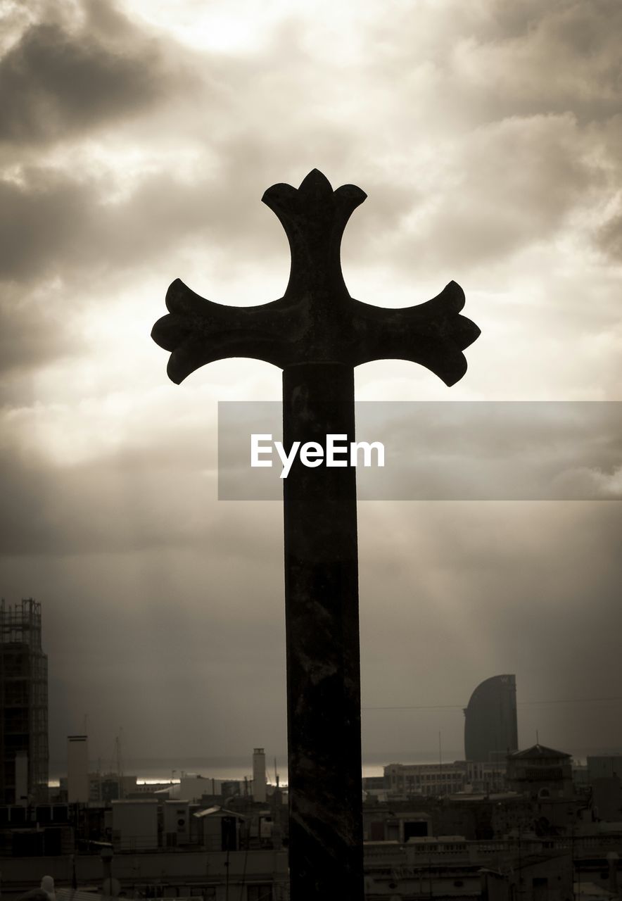 Low angle view of silhouette cross against cloudy sky at dusk