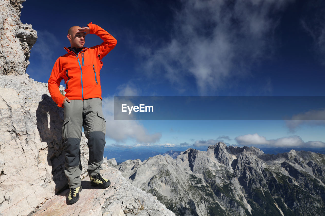 LOW ANGLE VIEW OF MAN STANDING ON ROCK