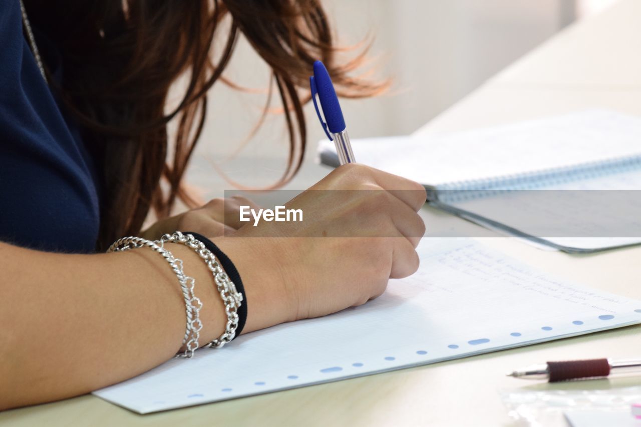 Cropped image of businesswoman writing in book at office