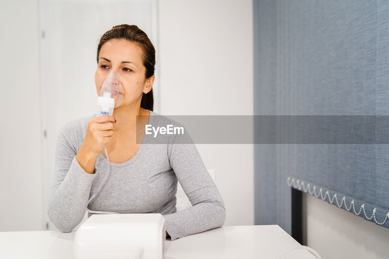 Woman holding nebulizer while sitting at table