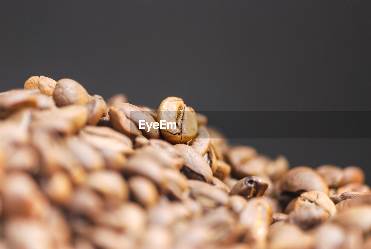 CLOSE-UP OF ROASTED COFFEE BEANS ON TABLE AGAINST BACKGROUND