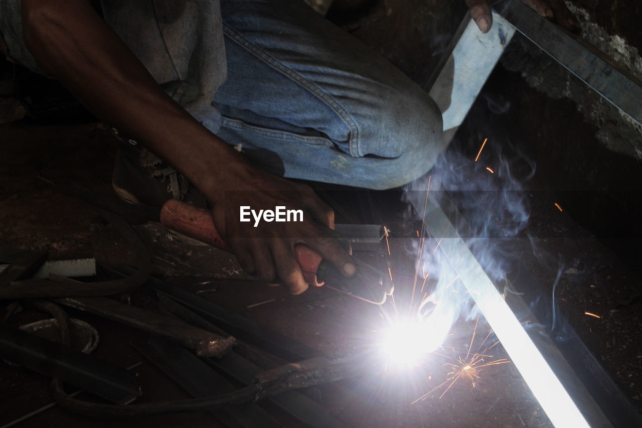 Low section of male worker welding at workshop