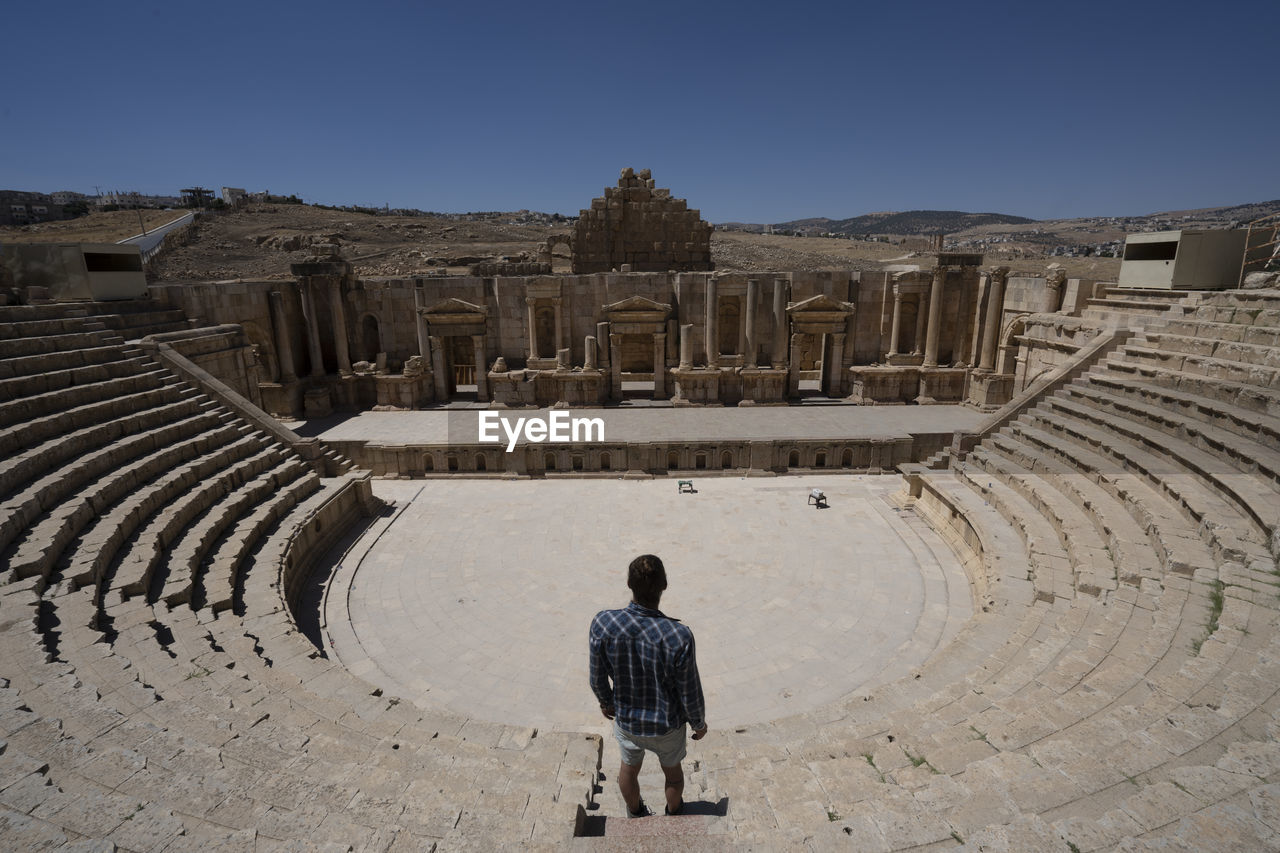 A man standing near the ancient roman theater in jerash, jordan