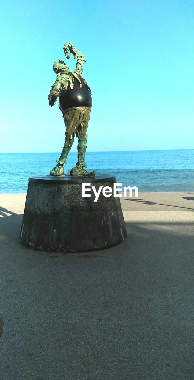 STATUE ON BEACH AGAINST CLEAR SKY