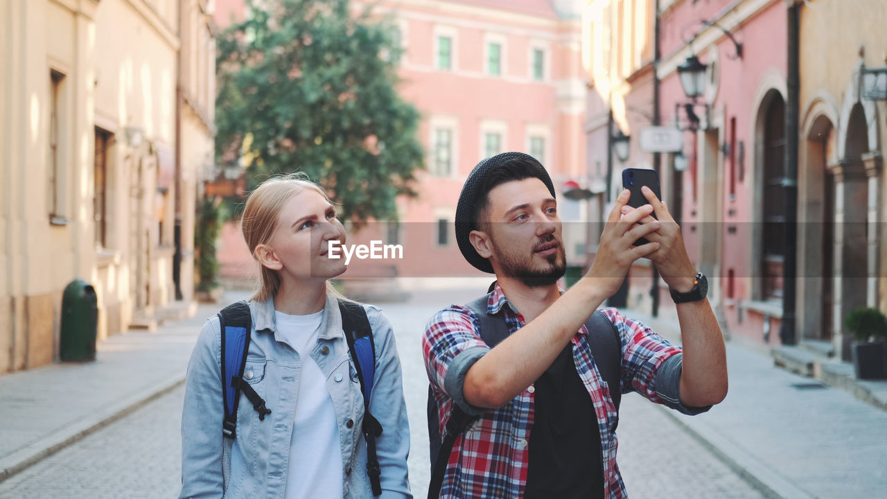 YOUNG COUPLE STANDING ON STREET IN CITY