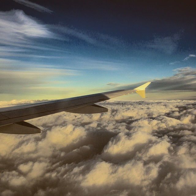 CROPPED IMAGE OF AIRPLANE WING OVER CLOUDS