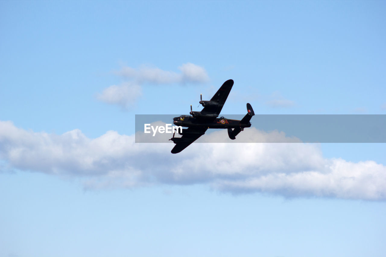 Low angle view of fighter airplane flying against blue sky