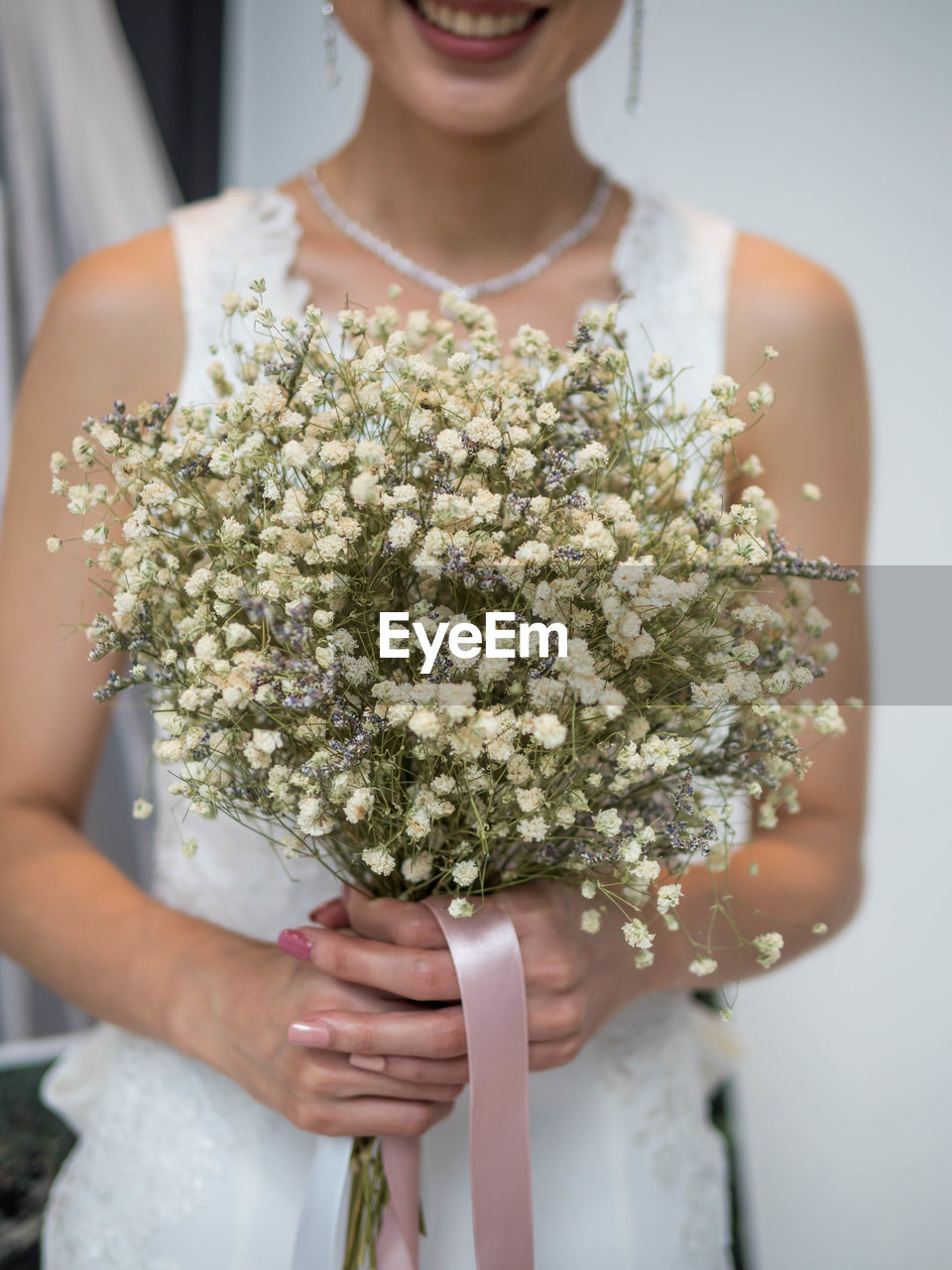 Midsection of bride holding flower bouquet during wedding ceremony