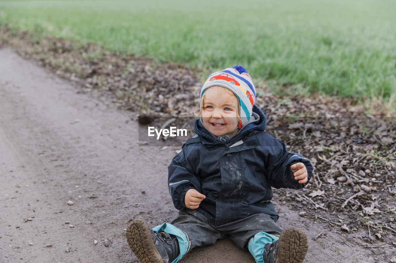 Smiling girl sitting on dirt road during winter