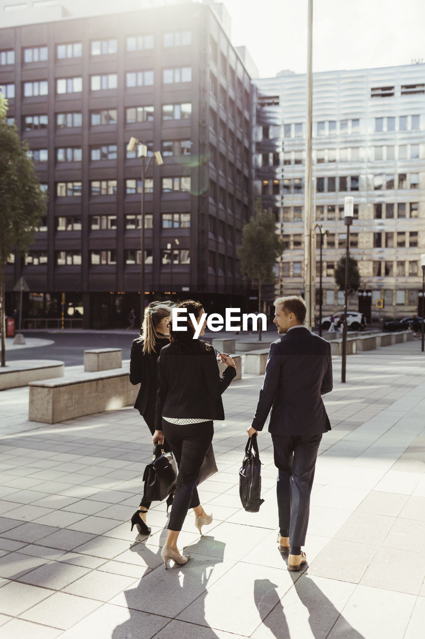 Rear view of entrepreneurs discussing business strategy while walking outdoors