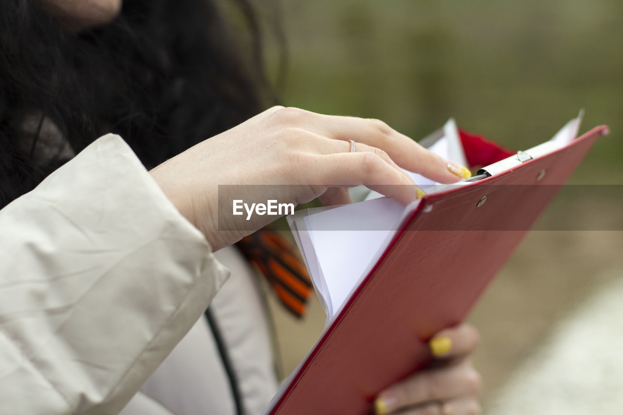 The secretary holds a tablet with papers. the girl is holding an office paper with text. 