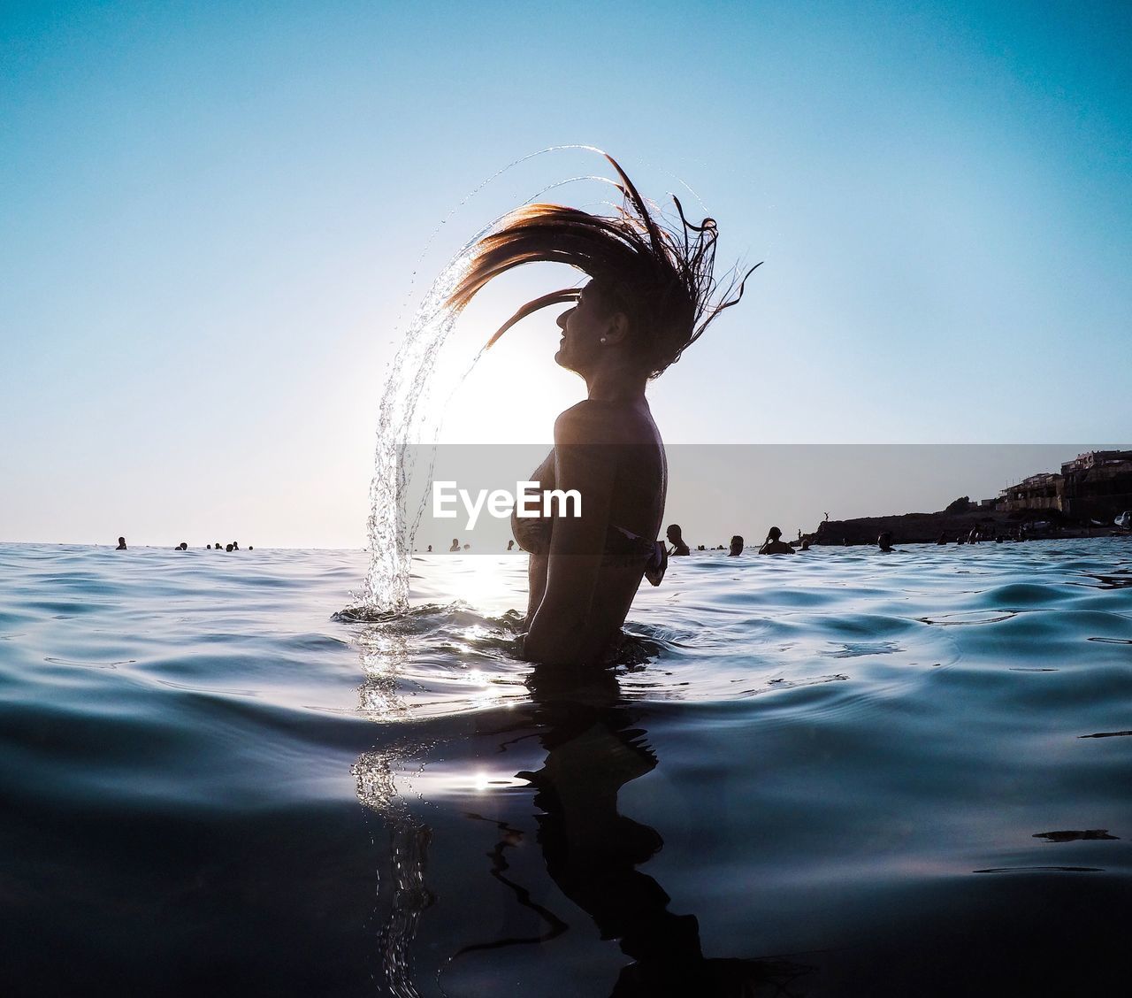 Woman with touseld hair swimming in sea against clear sky