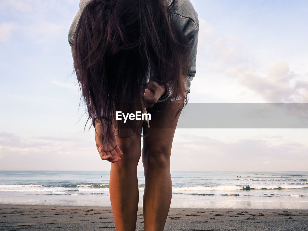 Woman standing at beach against sky