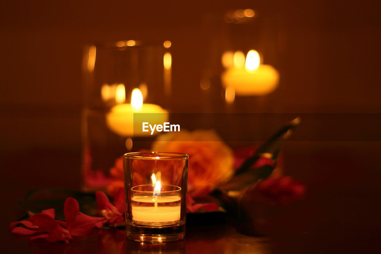 Close-up of lit tea light candle in glass on table