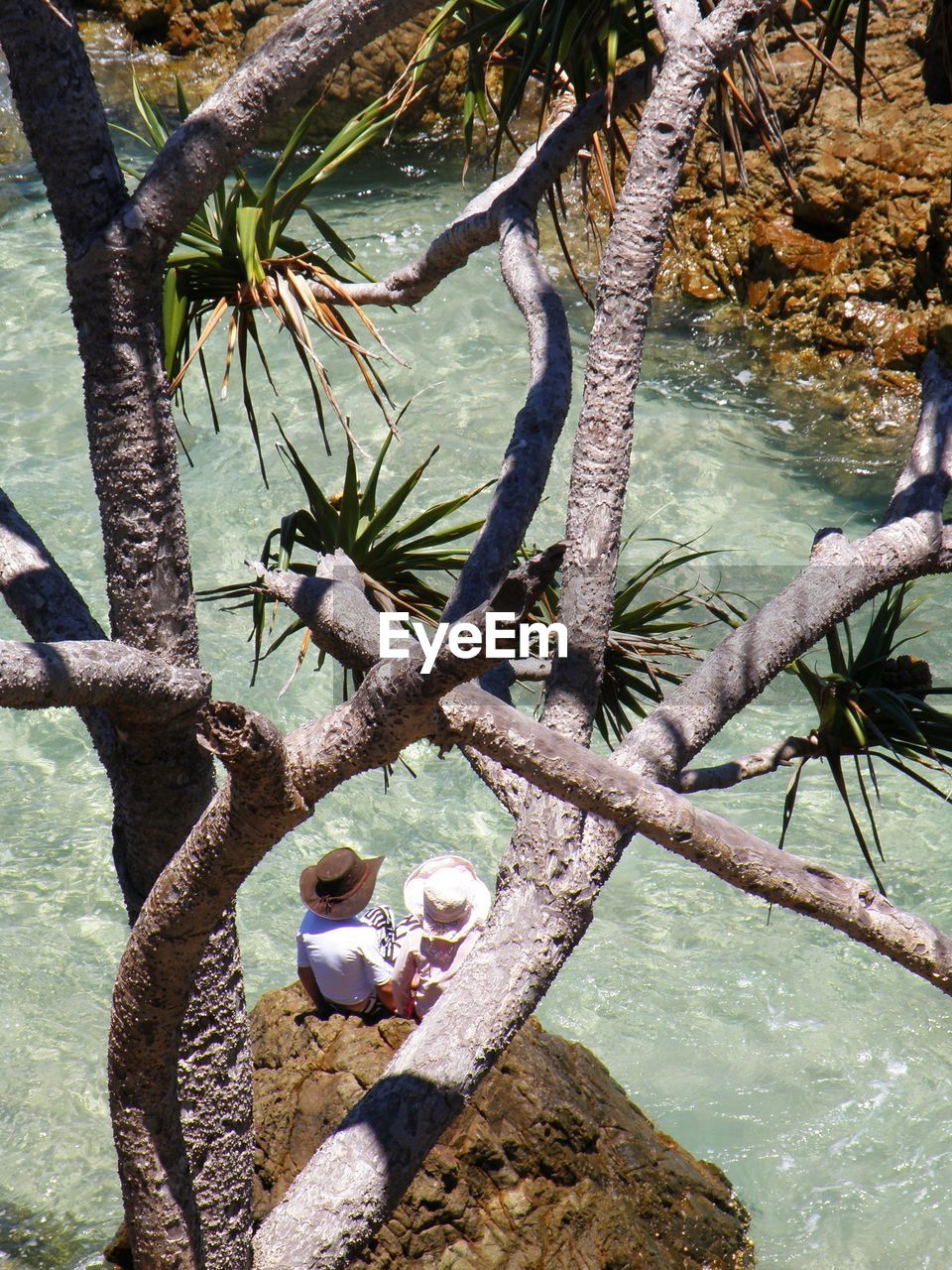 High angle view of man and woman sitting on rock amidst river