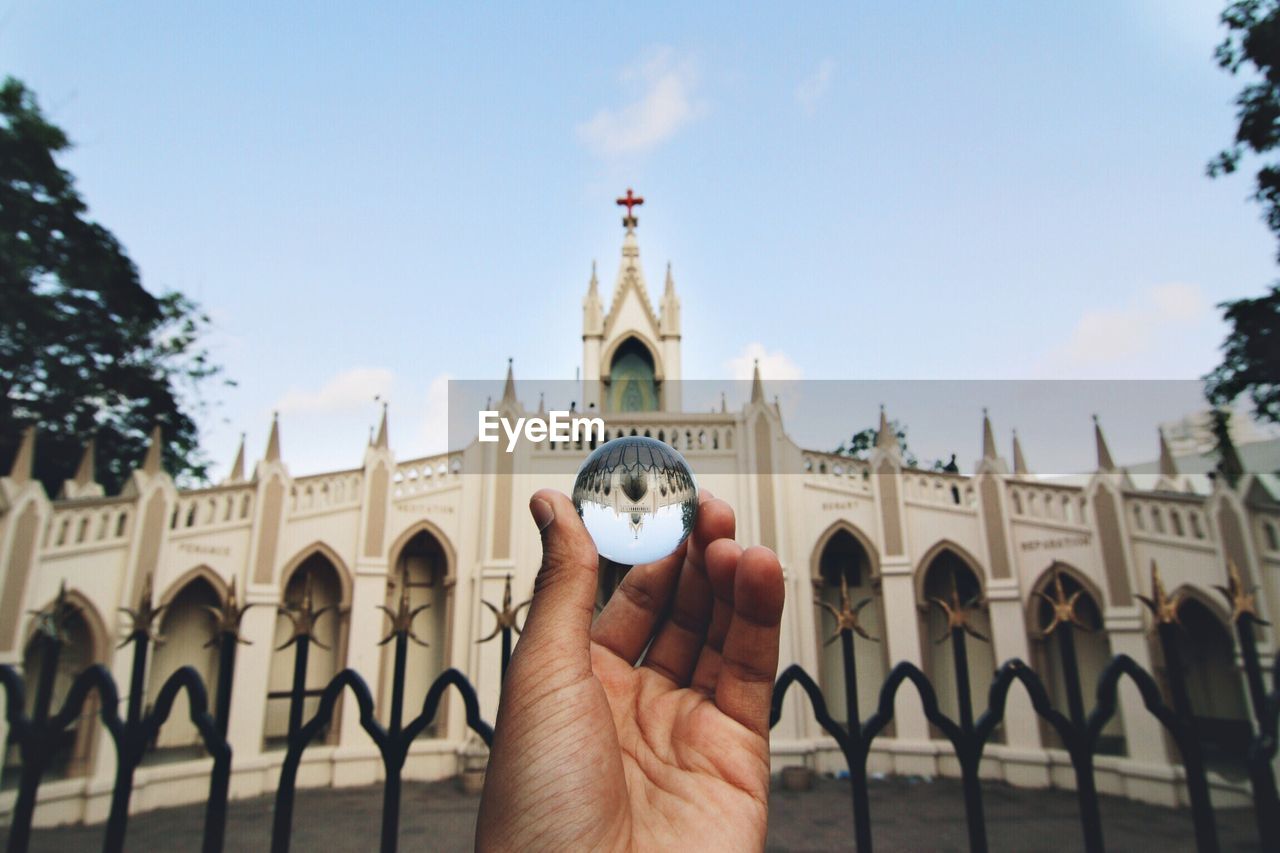 Hand holding glass ball view of church