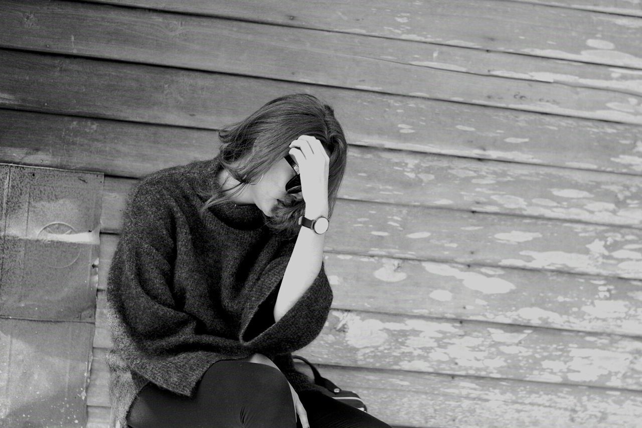 YOUNG WOMAN SITTING ON TILED FLOOR