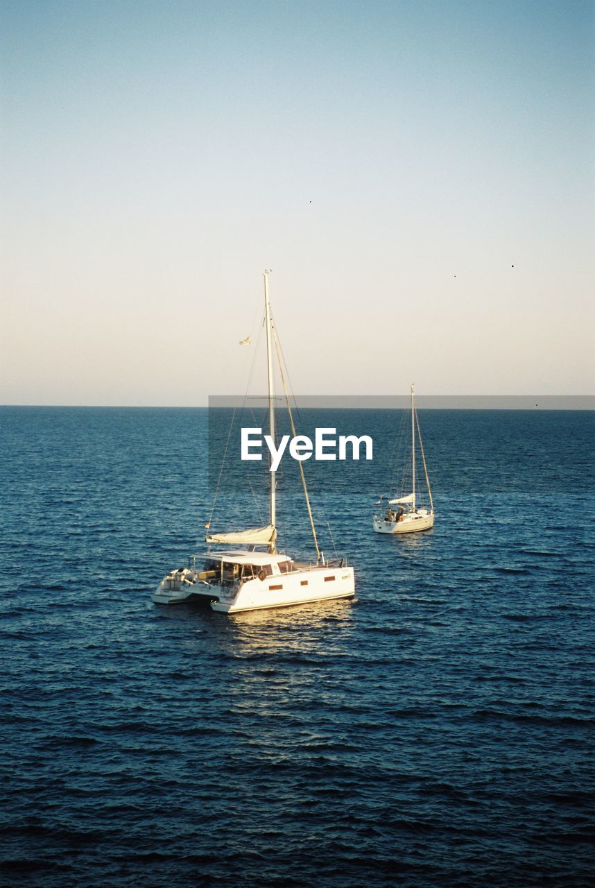 Sailboat sailing on sea against clear sky. shot on 35mm cinestill 50d film. 