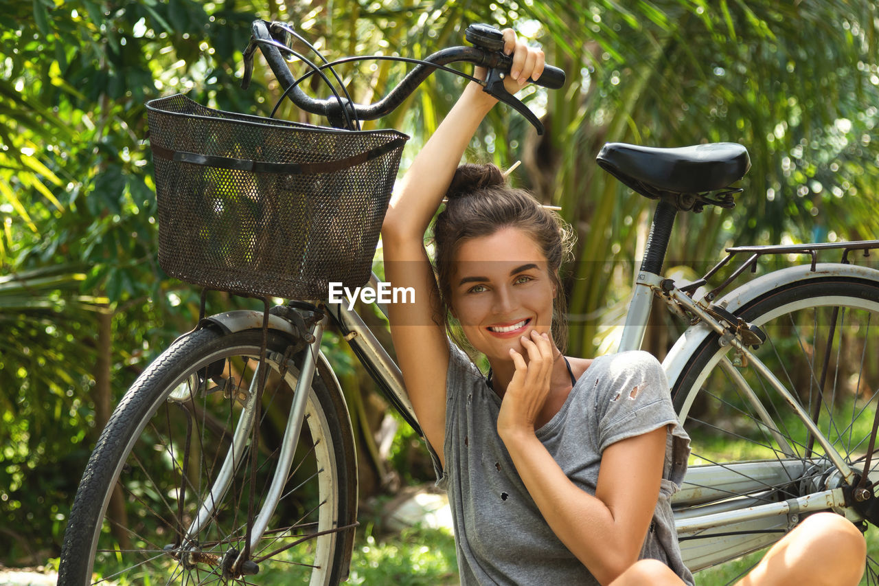 Portrait of woman sitting by bicycle