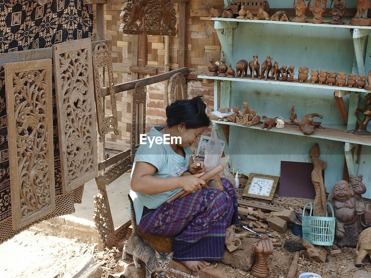 Woman craving wood while sitting at market