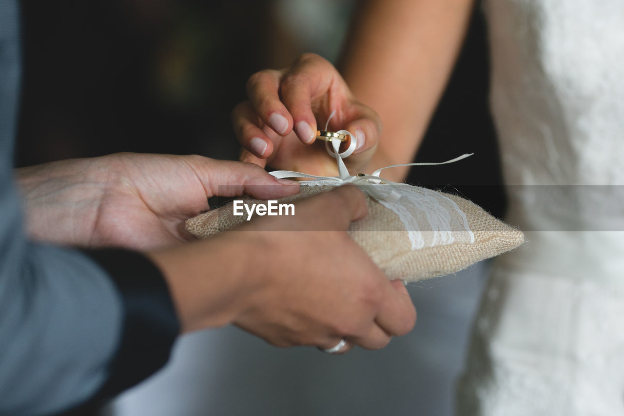 Midsection of bride holding ring given by bridesmaid during wedding