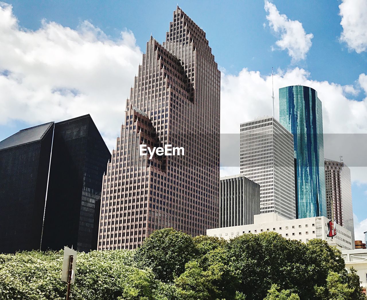 Low angle view of modern buildings against cloudy sky during sunny day