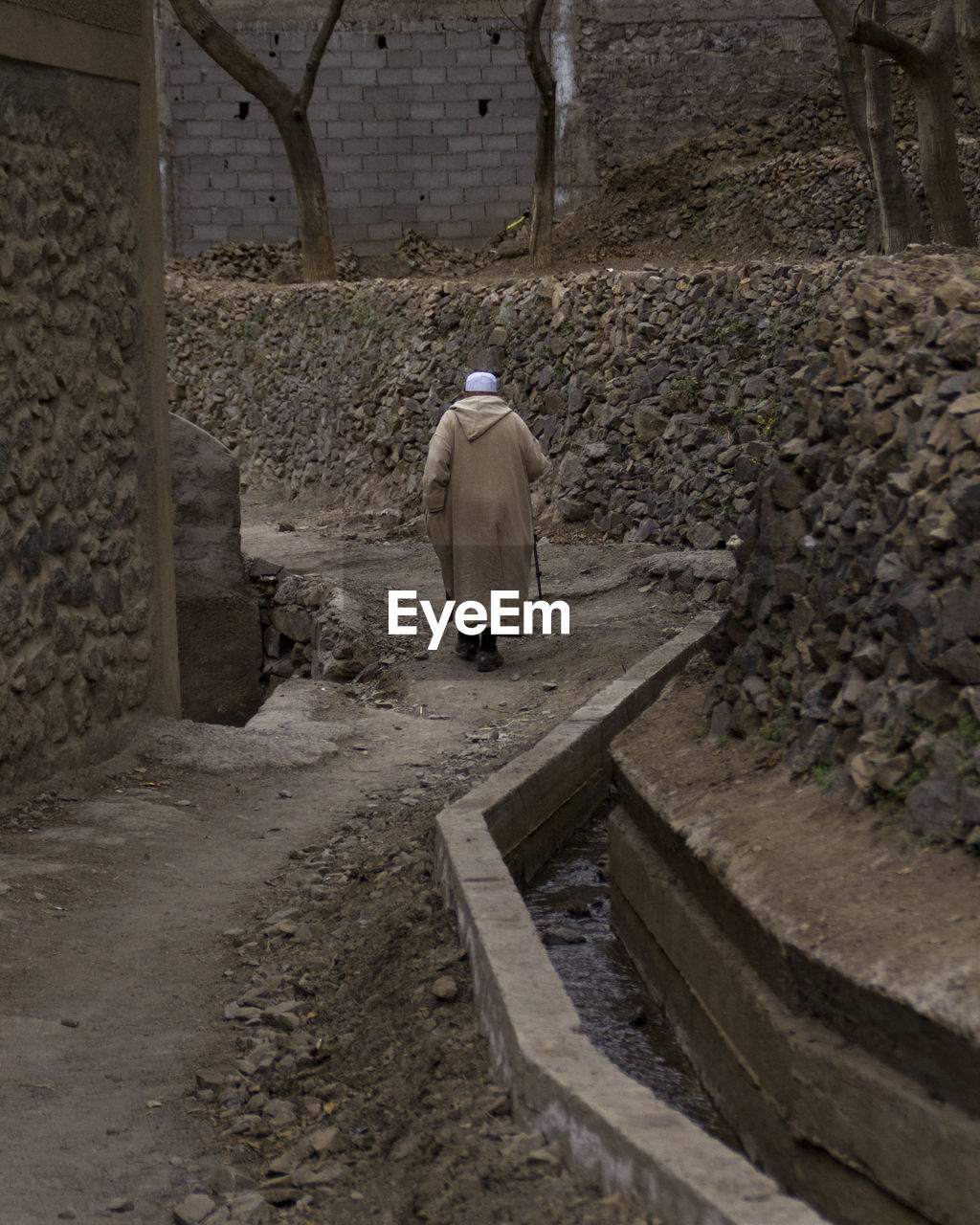 REAR VIEW OF MAN STANDING ON CONSTRUCTION SITE