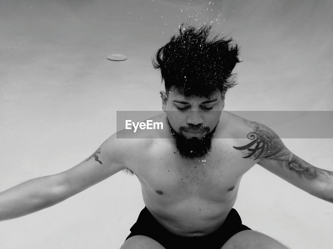 Man with tattoos swimming underwater