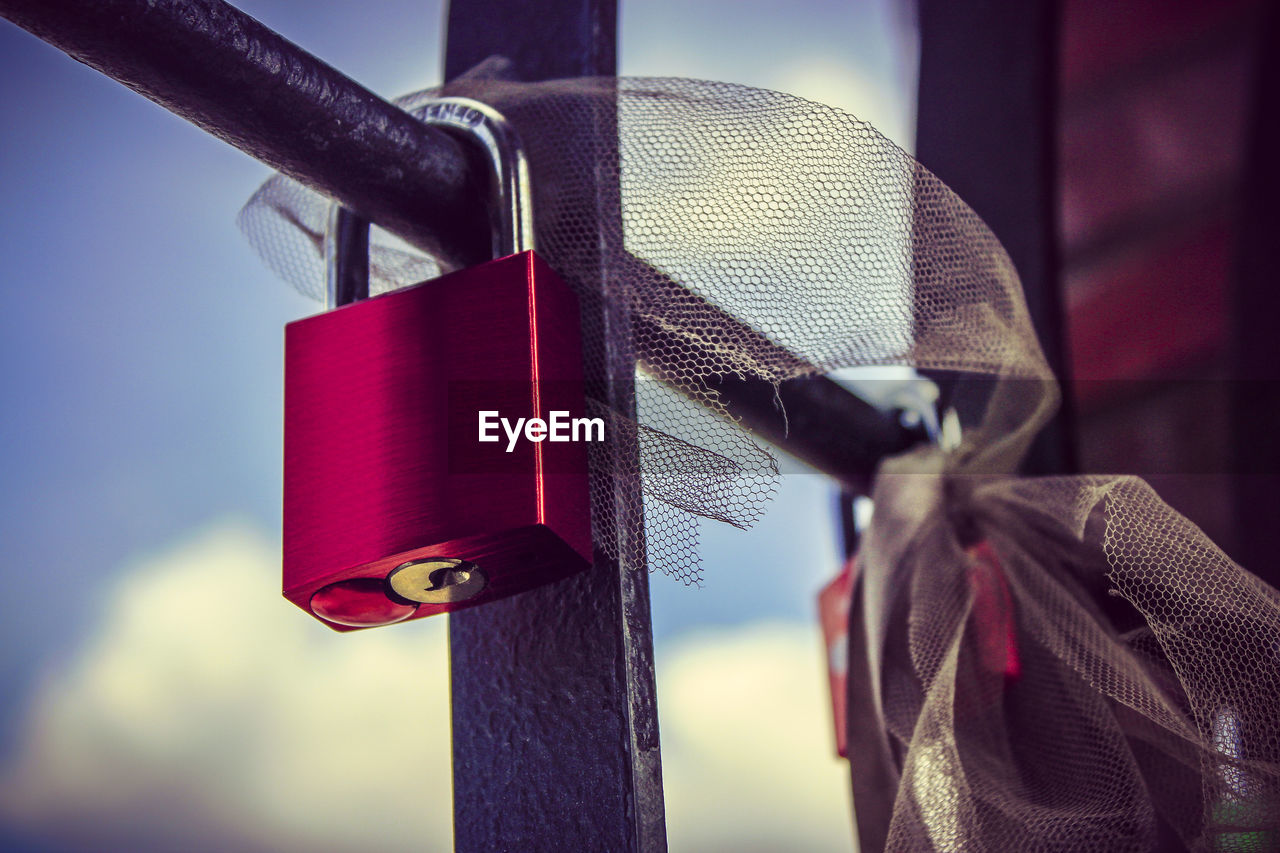 Close-up of padlock on railing against the sky
