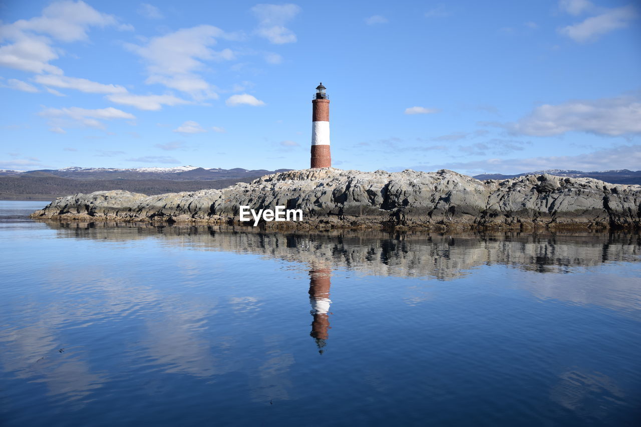 Lighthouse by sea against sky