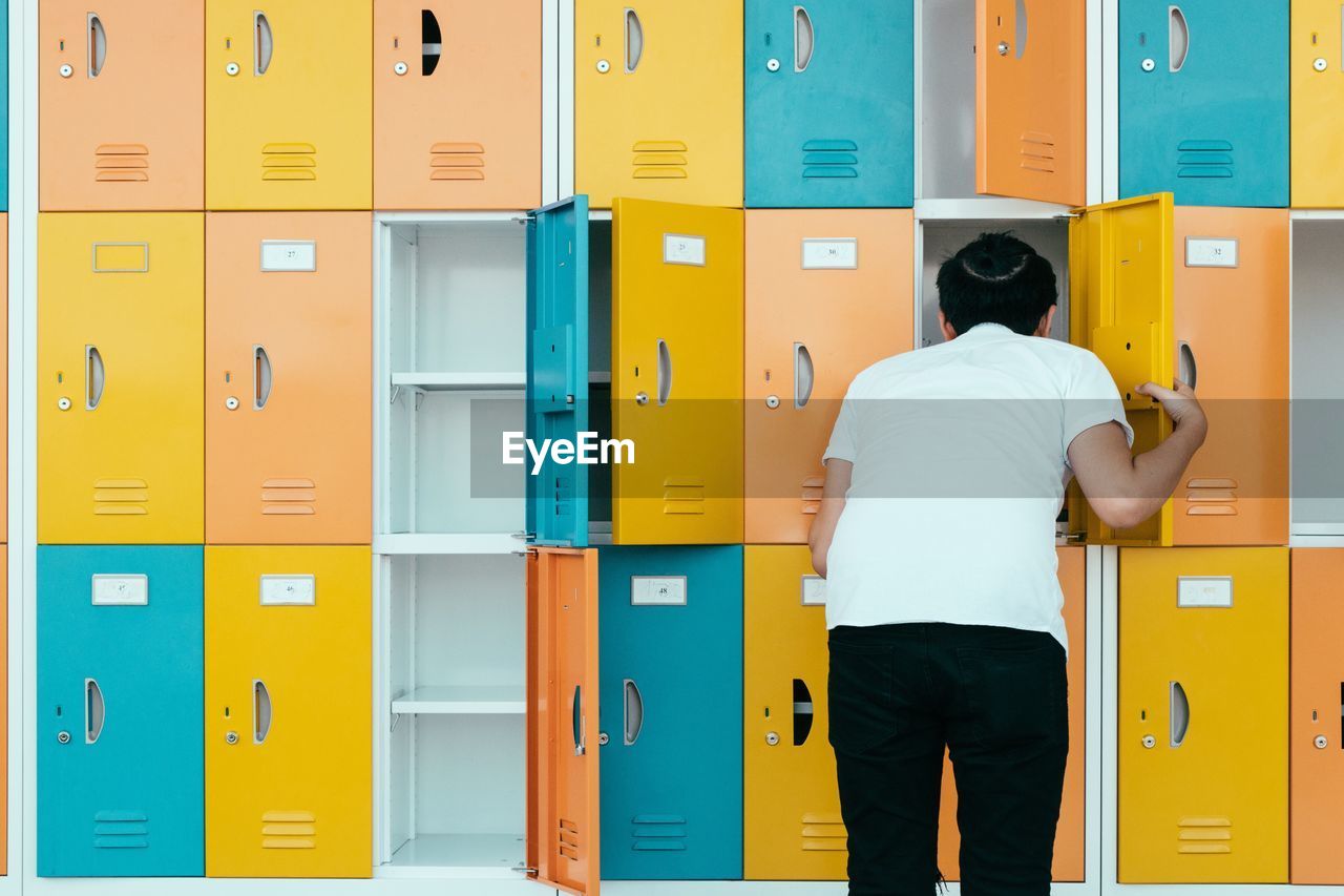 Rear view of man checking locker