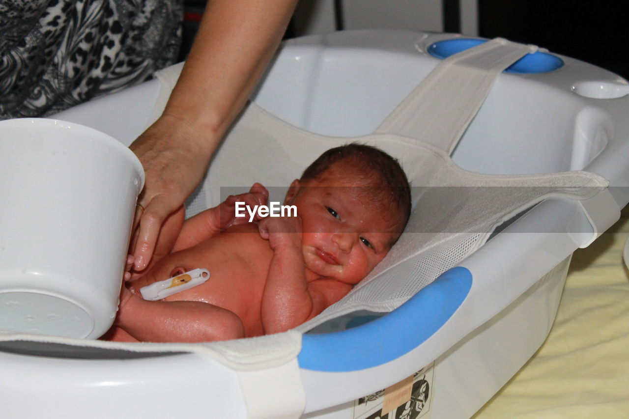 Woman giving bath to baby girl in bathtub