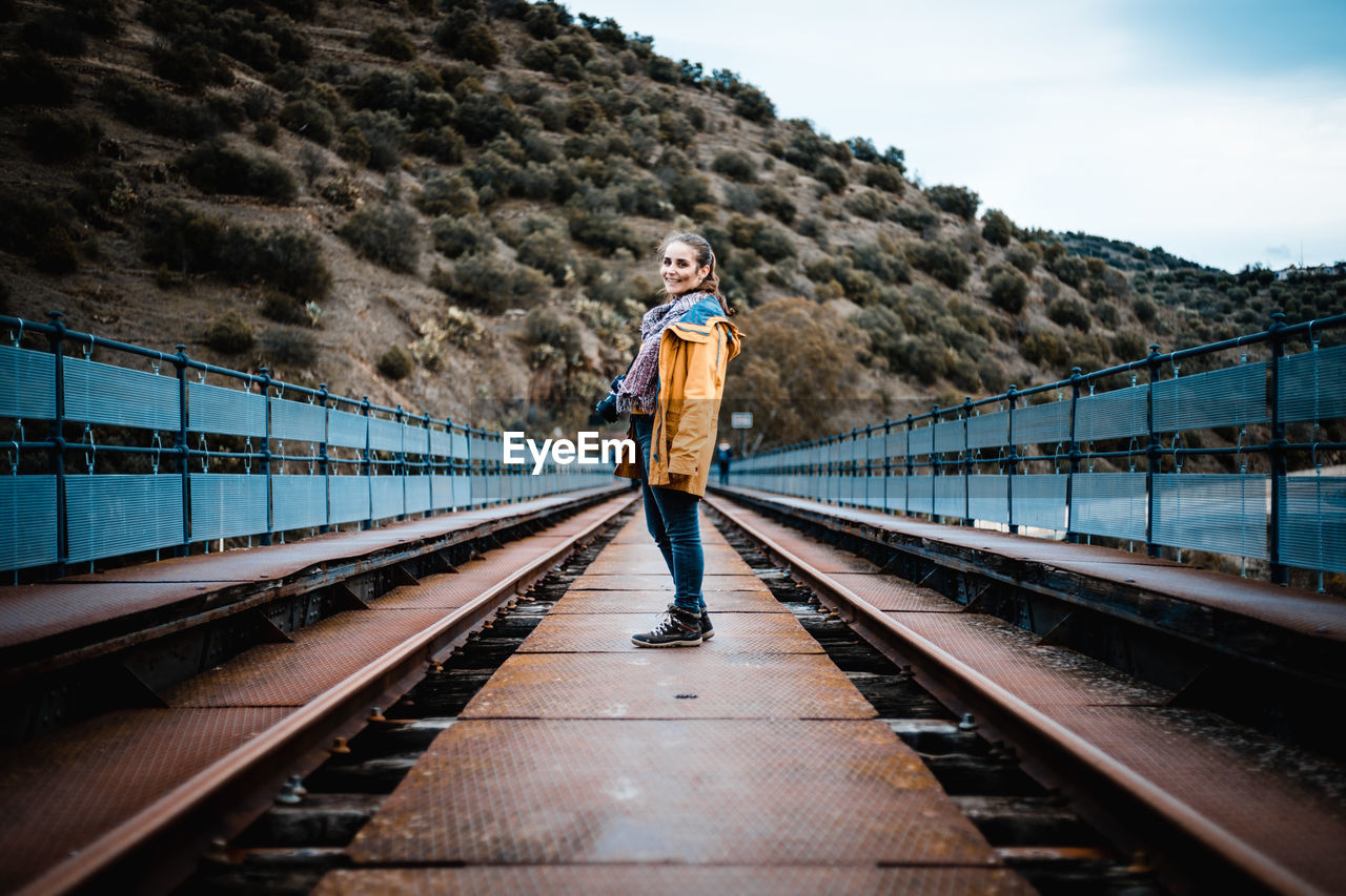 Portrait of young woman standing on railway bridge