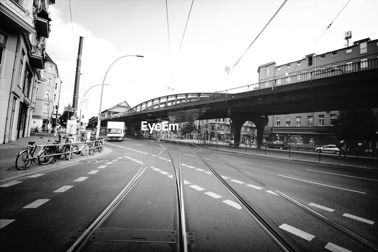 Tram tracks with bridge and buildings in city against clear sky