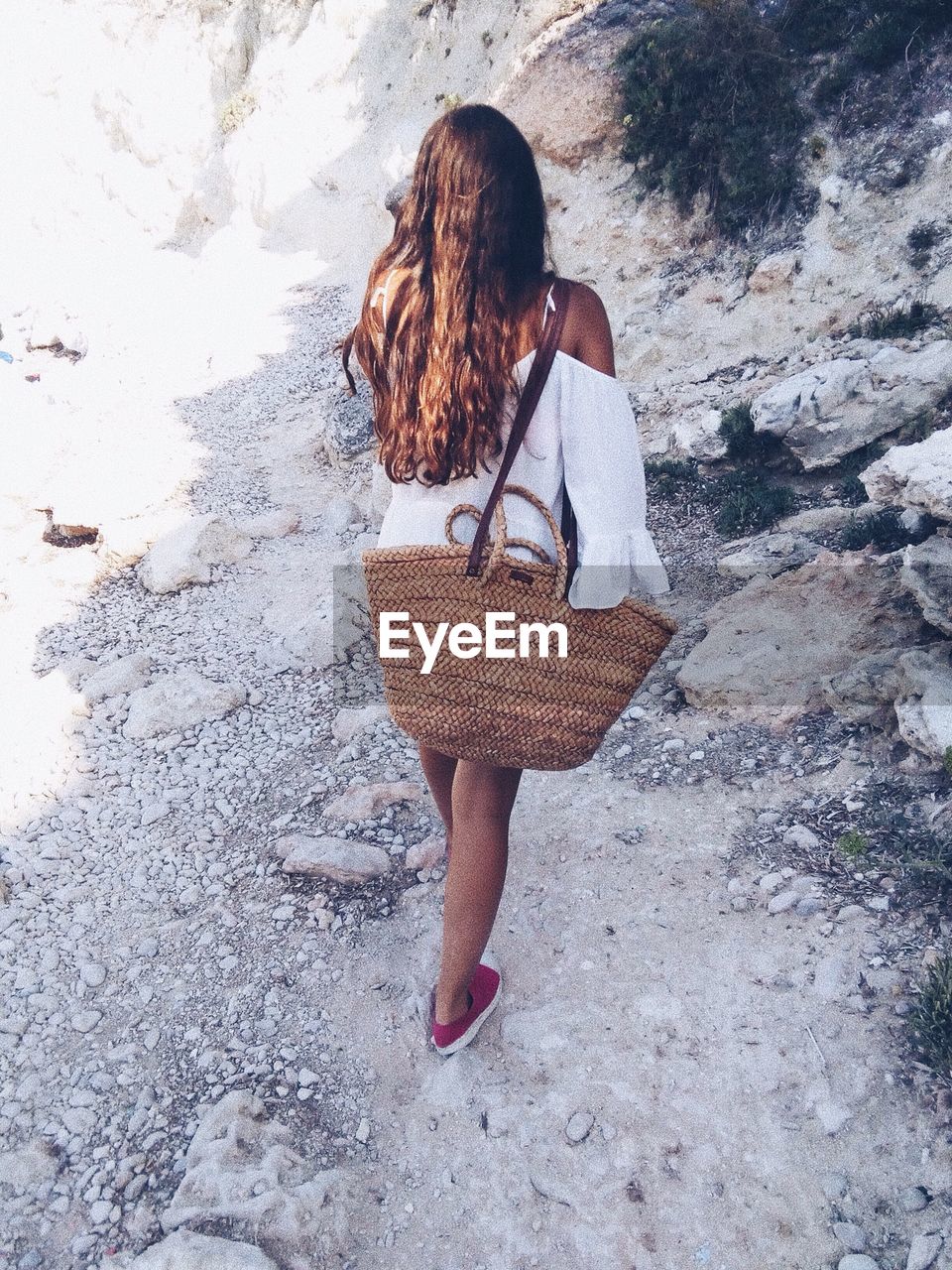 Rear view of woman with wicker basket walking at beach